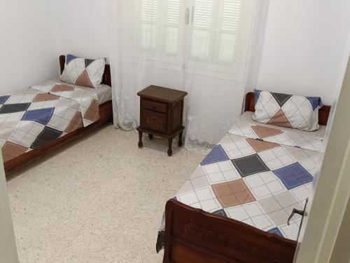 a bedroom with two beds and a nightstand in it at La Sirène BENI KHIAR TUNISIE AFRIQUE in Beni Khiar