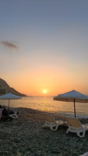 two chairs and umbrellas on a beach at sunset at chelh tiratine 