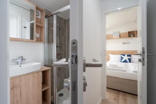 a small bathroom with a sink and a bed at Ostseecamp Küstenkind, eingezäuntes Grundstück in Scharbeutz