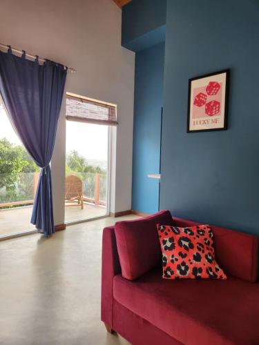 a living room with a red couch and a window at Belika Beach in Hiriketiya