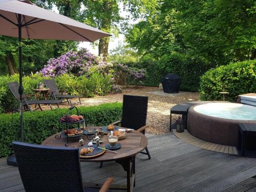 a patio with a table and an umbrella and a pool at Luxuszeit zu Zweit in Borchel