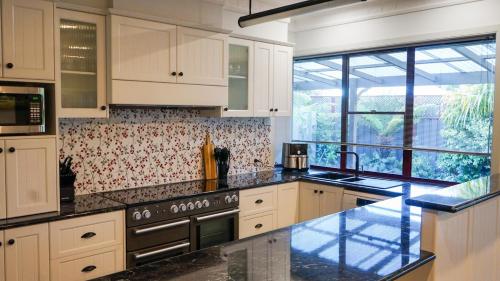 a kitchen with white cabinets and black counter tops at The Conductors Quarters in Bendigo