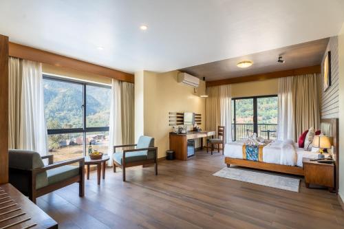 a bedroom with a bed and a desk and chairs at Triple Crown Resort in Dhāding
