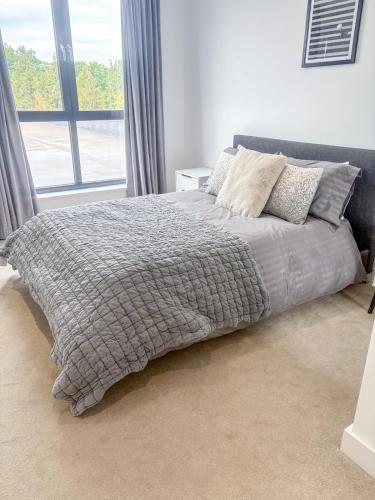 a bed with a gray blanket and pillows in a bedroom at Modern 1-Bedroom Flat near NEC, Solihull in Olton