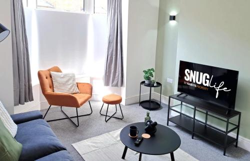 a living room with a blue couch and a tv at Modern Newly Refurbished 3-Bedroom House in Lincoln