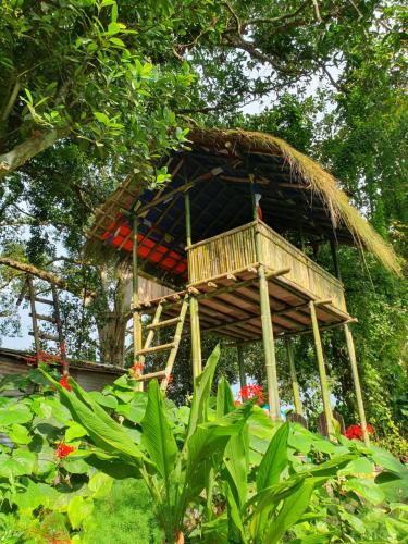 a tree house with a ladder in a garden at Pemsee's Tree Town - Eco-friendly,Tree house hostel in Sauraha