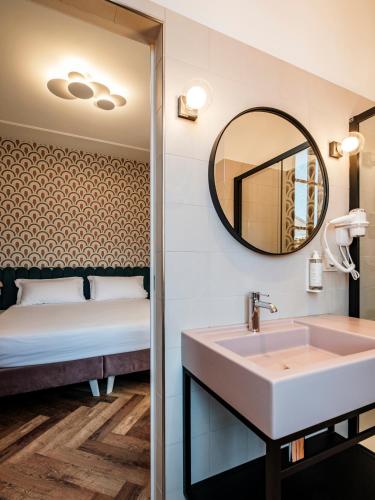 a bathroom with a sink and a mirror and a bed at Hotel Lory in Forlì