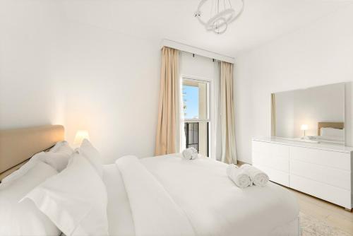 a white bedroom with a white bed and a mirror at FIRST CLASS 1BR Tranquility in Style in Abu Dhabi