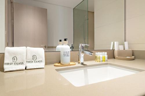 a bathroom with a sink with towels and a mirror at FIRST CLASS 1BR Tranquility in Style in Abu Dhabi