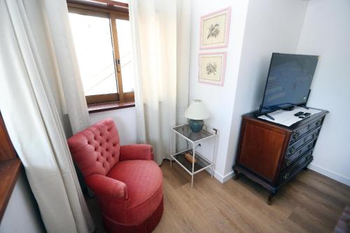 a living room with a red chair and a television at A Côrte Das Azenhas in Valença