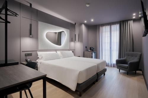 a bedroom with a white bed and a desk and chair at Hotel LIVVO La Escarlata in Las Palmas de Gran Canaria