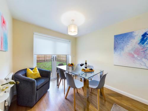 a dining room with a glass table and a chair at Modern Comfortable 2 & 3 Bed Apartments, Free Parking, Wifi, Headington, Close to Hospitals, Science Park & Brookes University in Oxford