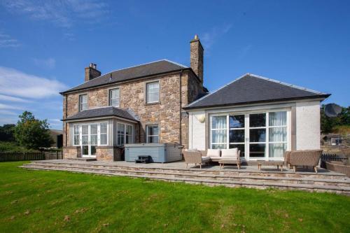 a house with a large patio with chairs and a grill at Stunning 4 Bedroom Farmhouse in Bishopton