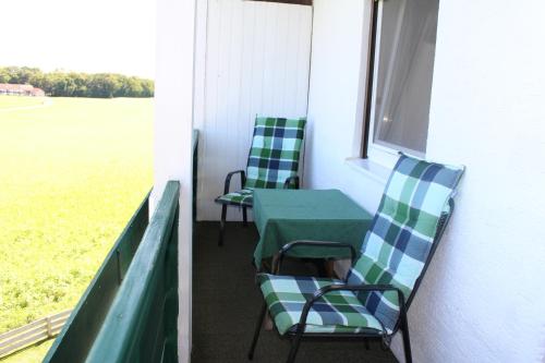 a porch with two chairs and a table and a field at Erwachsenen Aparthotel Naturidyll - Der Wieserhof in Bad Füssing