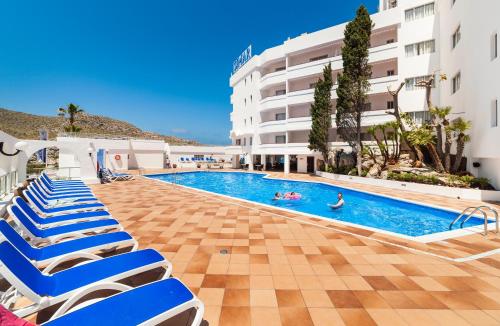 einen Pool mit Liegestühlen und ein Hotel in der Unterkunft Globales Simar in Cala de Sant Vicent