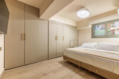 a bedroom with a bed and cabinets and a window at Azure Sofia - Grounded in Kos