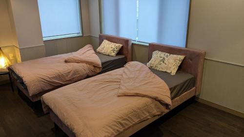 two beds sitting in a room with a window at Takayama Fortune-inn in Takayama