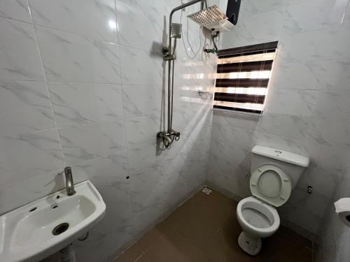 a white bathroom with a toilet and a sink at CampDavid Luxury Apartments Ajao Estate Airport Road Lagos 0 8 1 4 0 0 1 3 1 2 5 in Lagos