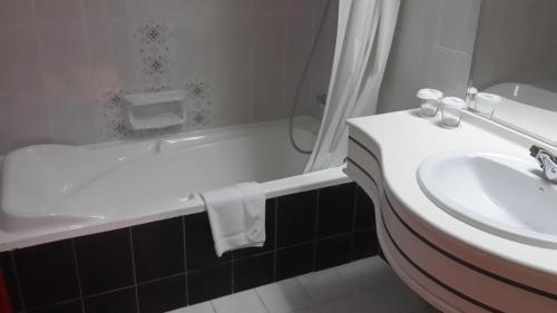 a bathroom with a sink and a tub and a toilet and a sink at Dubai Grand Hotel by Fortune, Dubai Airport in Dubai