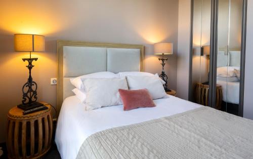 a bedroom with a large white bed with two lamps at Auberge du Chateau Bleu in Tremblay En France