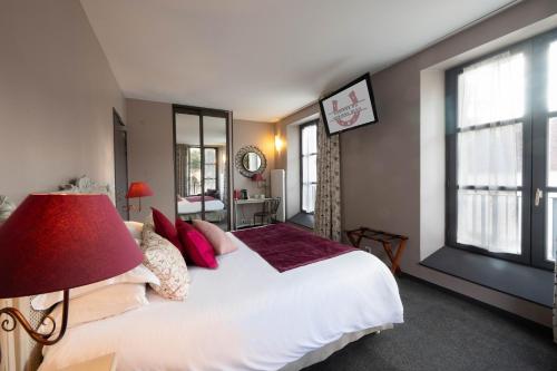 a bedroom with a large bed and a red lamp at Auberge du Chateau Bleu in Tremblay En France