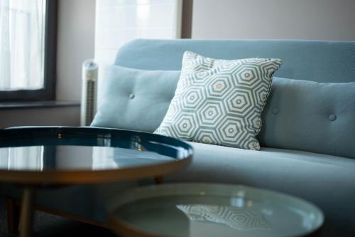 a blue couch with a pillow and a coffee table at Auberge du Chateau Bleu in Tremblay En France