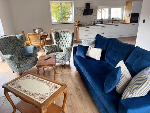 a living room with a blue couch and chairs at Dom przy lesie in Koniecwałd