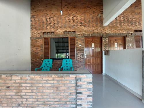 two blue chairs sitting in front of a brick wall at Gondang Sivali Hotel in Tomok