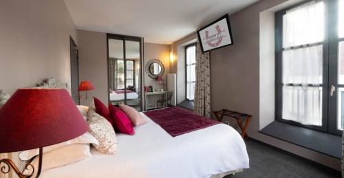 a bedroom with a large white bed with a red lamp at Auberge du Chateau Bleu in Tremblay En France
