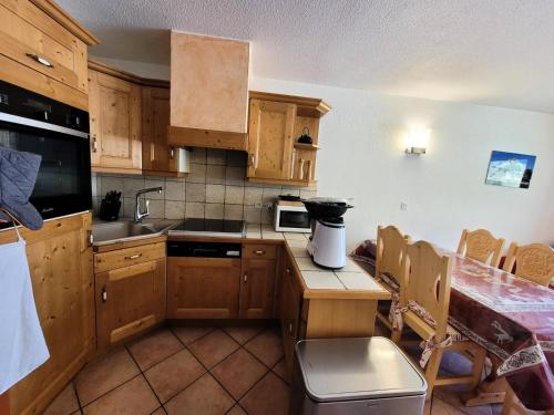 a kitchen with wooden cabinets and a table with a counter at Résidence Les Balcons Des Curtious - Appartement 3 pièces - 6 personnes MAE-2183 in Bessans