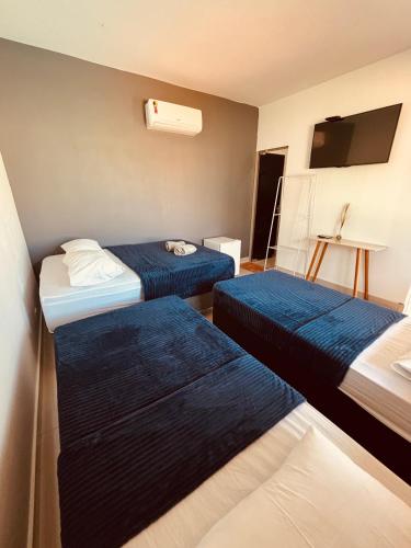 a hotel room with two beds and a television at Pousada Duarte in Capitólio