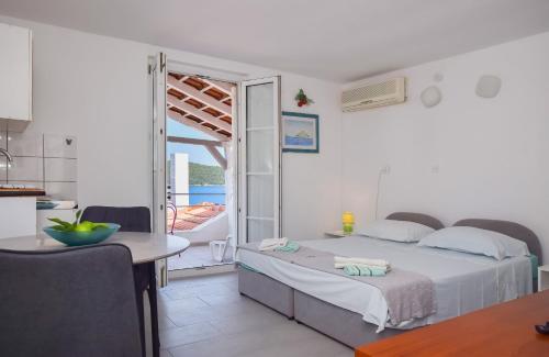 Un dormitorio con una cama y una mesa y una cocina. en Apartments Dubravka, en Nečujam