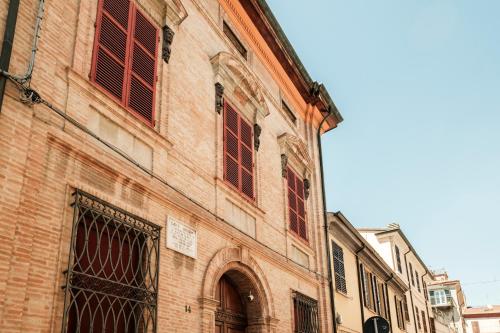 a brick building with red windows on a street at Hotel Lory in Forlì