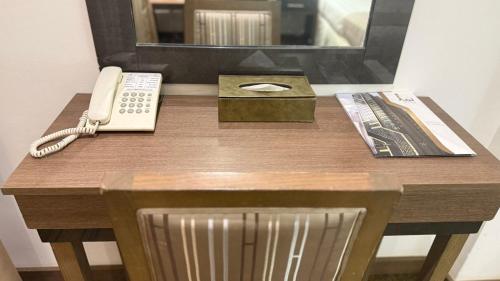 a desk with a phone and a mirror and a chair at Lamar Ajyad First Hotel Tower A in Makkah
