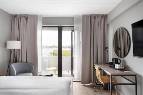 a hotel room with a bed and a desk and a window at Radisson Hotel Haugesund in Haugesund