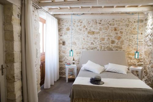 a bedroom with a bed and a stone wall at AC Homes Alice in Rethymno