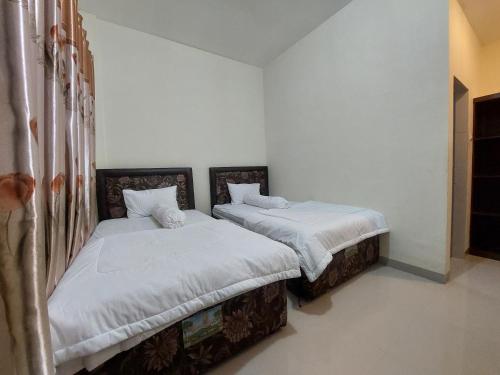 two beds sitting next to each other in a room at Gondang Sivali Hotel in Tomok