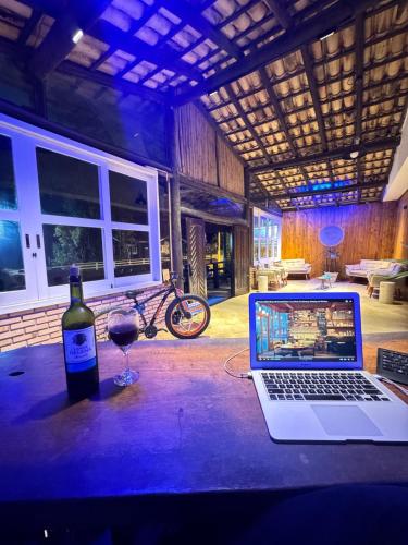 a bottle of wine and a laptop on a table at Pousada Barra do Sahy in Barra do Sahy
