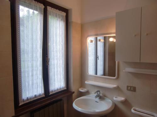 baño con lavabo, espejo y ventana en Appartamento Belvedere en Molina di Ledro