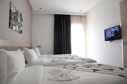 two white beds in a hotel room with a tv at Hotel A44 in Tetouan