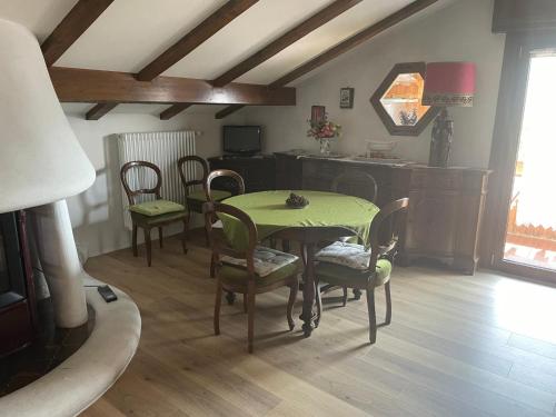 a dining room with a green table and chairs at Mansarda Cadore in Pieve di Cadore