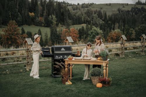 a group of three women standing around a grill at Owczarnia Tatry in Bukowina Tatrzańska