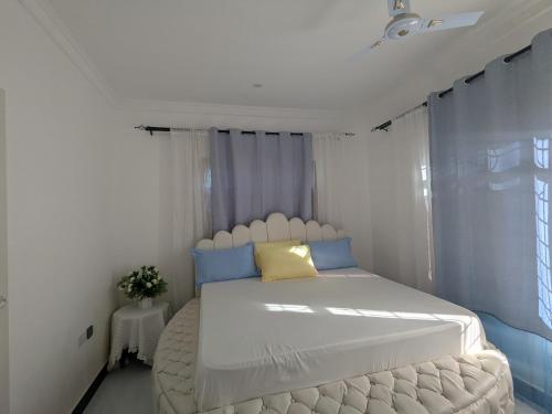 a bedroom with a white bed with blue and yellow pillows at Malaika White House Apartment & Spa in Kiwengwa