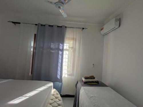a white room with a bed and a window at Malaika White House Apartment & Spa in Kiwengwa