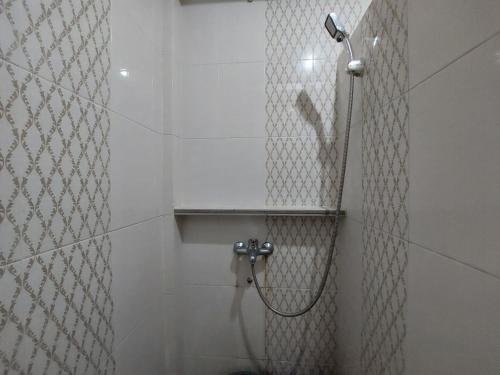 a bathroom with a shower in a white tiled wall at Gondang Sivali Hotel in Tomok