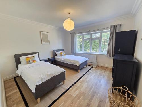 a bedroom with two beds and a window at Spacious 6 Bedroom house, Luton in Luton