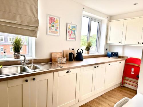 a kitchen with white cabinets and a sink and a window at New Five bed house with parking in St leonards in St. Leonards