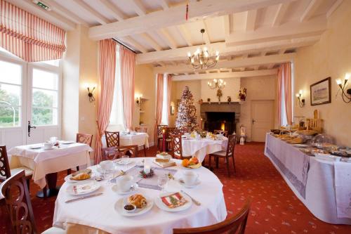 a dining room with white tables and a christmas tree at Hotel Spa La Malouinière Des Longchamps - Saint-Malo in Saint-Jouan-des-Guérets