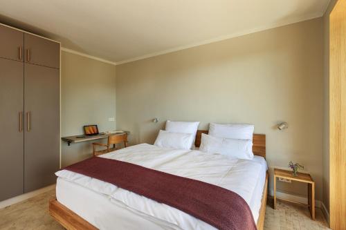 a bedroom with a large bed with white sheets and pillows at SEEZIEGE Uckermark - Ferienwohnungen am Carwitzer See in Thomsdorf