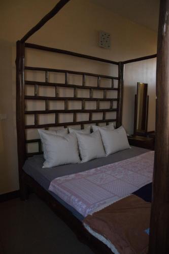 a bed with a wooden headboard and white pillows at Tai Africa Guest Rooms in Arusha